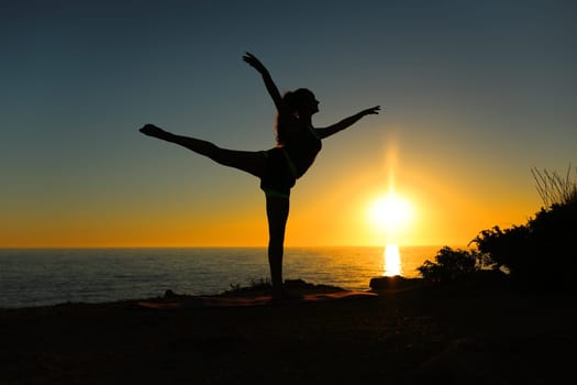 Woman silhouette dancing ballet at sunset on the beach