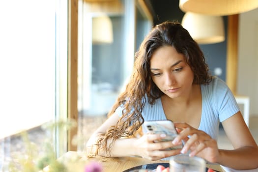 Woman using cell phone sitting in a restaurant