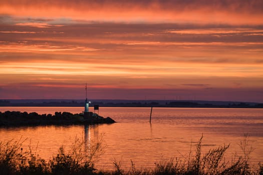 Sunset in Sweden at the harbor of lake Vaettern. Lighthouse in the background at dusk. Landscape shot in Scandinavia.