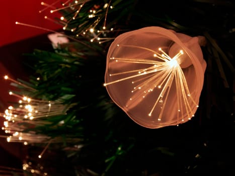 Details of a fibre-optic decorated Christmas Tree against a red wall