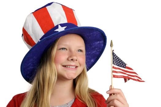 A pretty little girl in a patriotic American hat holding a flag and looking into the distance.