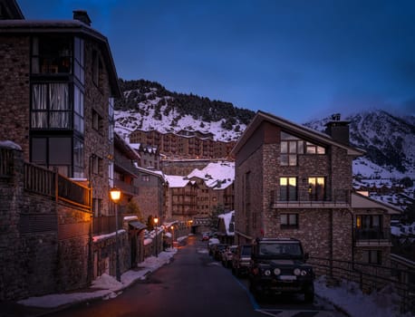 Narrow, cosy streets and modern stone houses and apartments in El Tarter village at dusk or night fall in Pyrenees mountains, Grandvalira, Andorra