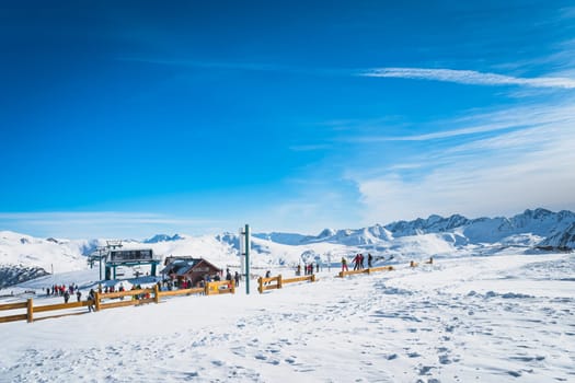 People, skiers and snowboarders getting ready to get on a slopes near ski lift on the top of the mountain, Andorra, El Tarter, Pyrenees Mountains