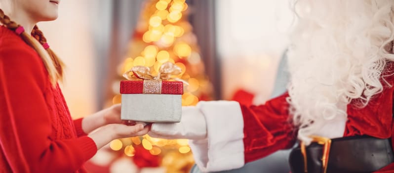 Hands of Santa Claus giving giftbox to the child. Concept of Christmas and New Year.