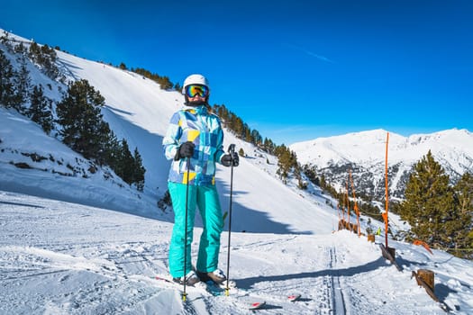 Portrait of a woman skier with ski on, looking at camera with slopes behind, Pyrenees Mountains. Winter ski holidays in El Tarter, Grandvalira Andorra