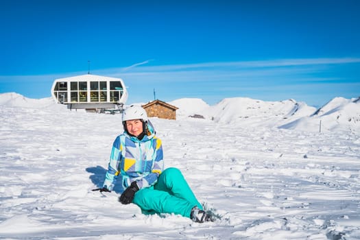 Close up portrait of a woman skier sitting on the snow and looking at camera Pyrenees Mountains. Winter ski holidays in El Tarter, Grandvalira Andorra