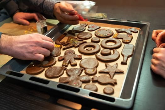A group of friends prepares ginger cookies of different shapes before Christmas.