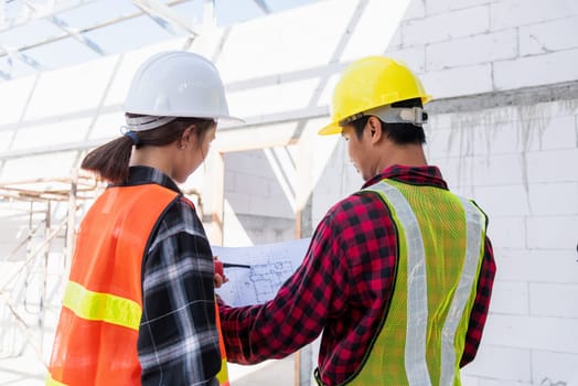 Architect and client discussing the plan with blueprint of the building at construction site. Asian engineer foreman worker man and woman working talking on drawing paper to checking project