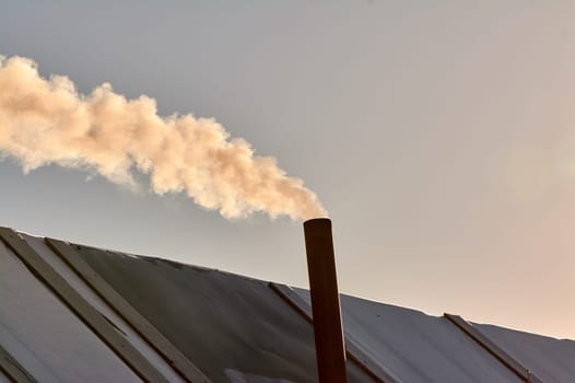 smoke is coming from the chimney of the bourgeoisie. the stove is being heated. High quality photo