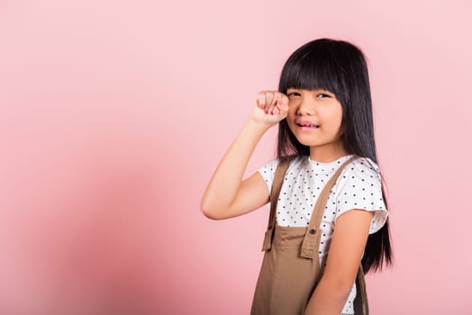 Unhappy children. Asian little kid 10 years old bad mood her cry wipe tears with fingers at studio shot isolated on pink background, child girl stress feeling sad unhappy crying
