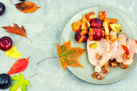 Juicy pork shoulder with skin and bacon cooked with plums. Top view
