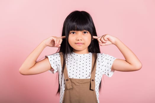 Asian little kid 10 years old Close her ears with fingers and eyes at studio shot isolated on pink background, child girl does not want to listen, Stress and noise concept