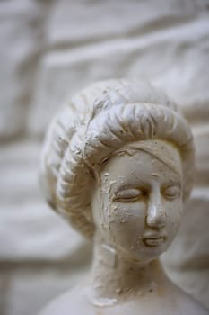 The head of a restored female figure on a white stone wall.