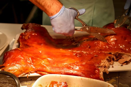A grilled suckling pig is expertly carved by a chef.