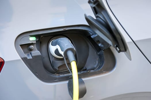 An electric car is charged at a charging station using a charging cable.