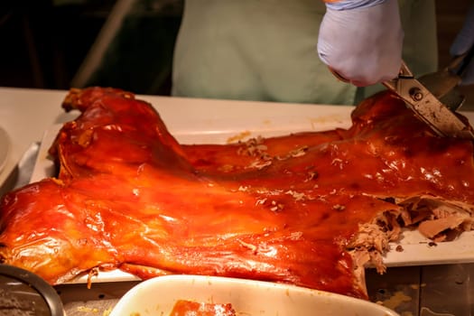 A grilled suckling pig is expertly carved by a chef.