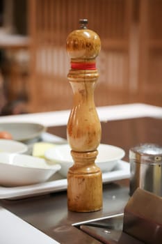 A wooden pepper mill stands next to the hob of a kitchen.