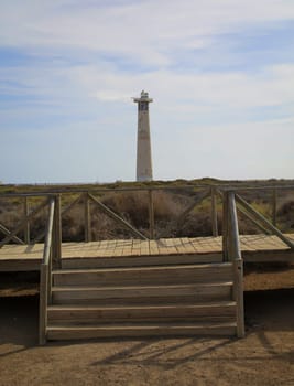 The view through a staircase to a lighthouse on the coast.