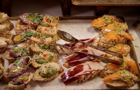 Many tapas, small baguettes pieces with toppings on a board.