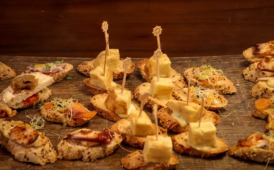 Many tapas, small baguettes pieces with toppings on a board.