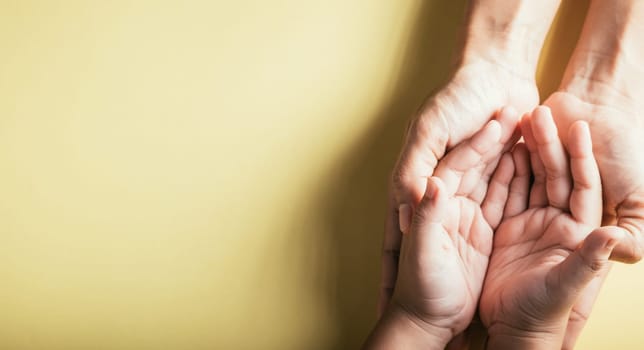 Close up hands children on adult mother hand, Top view person kid stack mom palms, Parents and little kid holding empty hands together isolated on yellow background, Family day care concept