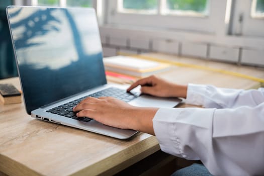 Back to school. Close up hands of female using computer sitting at school table, Young woman teacher with laptop at desk in classroom, Online education and technology learning concept