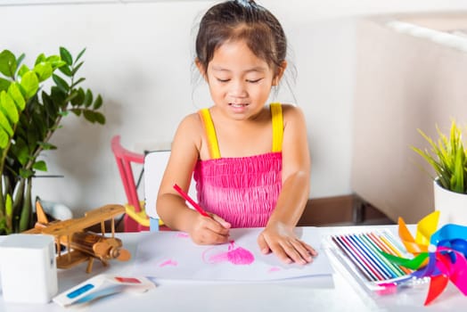 Happy child little girl colorful drawing pink heart on white paper, Asian cute kid preschooler smiling draw color love picture card at home, Valentine's or Mother's Day or Father's Day