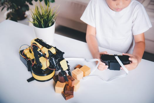 Happy Asian little boy using remote control playing robotic machine arm for pick up wood block, Funny learning successful getting a lesson control robot arm, Technology science education concept