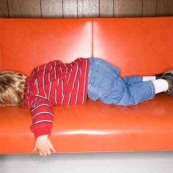 Caucasian boy sleeping on vinyl sofa.