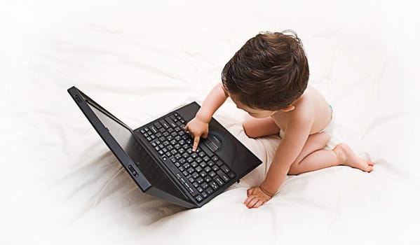 baby looking at laptop computer on bed