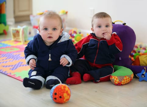 Cute baby brothers playing in the nursery