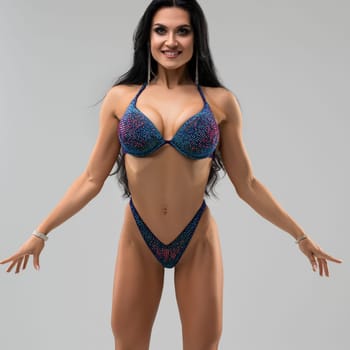 A fitness model showcases toned muscles and an athletic physique in a vibrant swimsuit, highlighting strength and dedication.