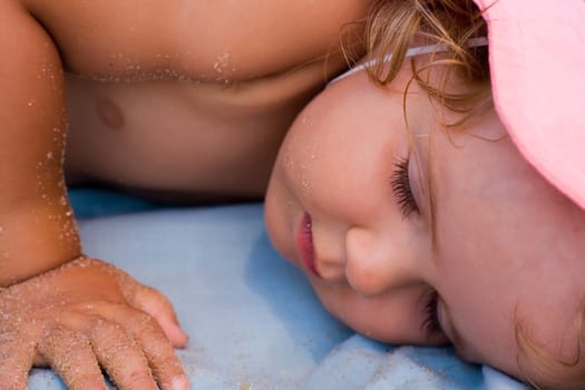 Baby girl taking a nap after playing on the beach