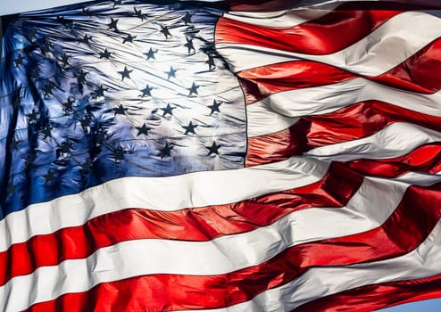 Backlit American Flag Waving In Wind Against a Deep Blue Sky.