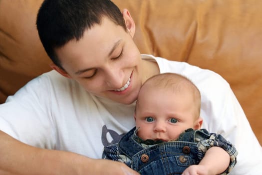 happy teenage boy playing with a baby