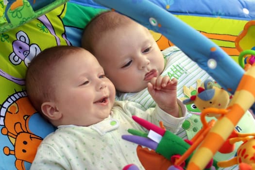 Two baby boys twin brothers playing together