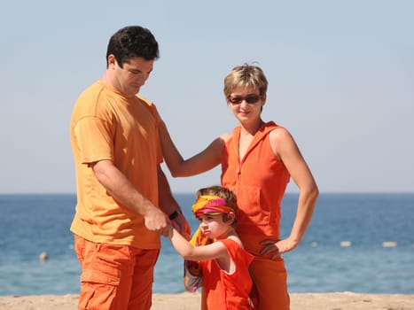 Family in orange clothes on the beach