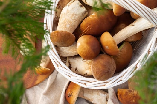 White wicker basket with boletus mushrooms. Top view.