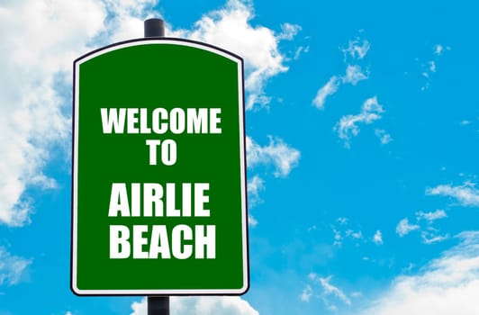 Green road sign with greeting message WELCOME TO AIRLIE BEACH isolated over clear blue sky background with available copy space. Travel destination concept  image