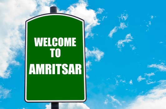 Green road sign with greeting message WELCOME TO AMRITSAR isolated over clear blue sky background with available copy space. Travel destination concept  image