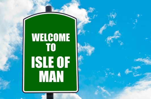 Green road sign with greeting message WELCOME TO  ISLE OF MAN isolated over clear blue sky background with available copy space. Travel destination concept  image