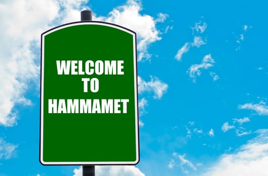Green road sign with greeting message WELCOME TO HAMMAMET isolated over clear blue sky background with available copy space. Travel destination concept  image