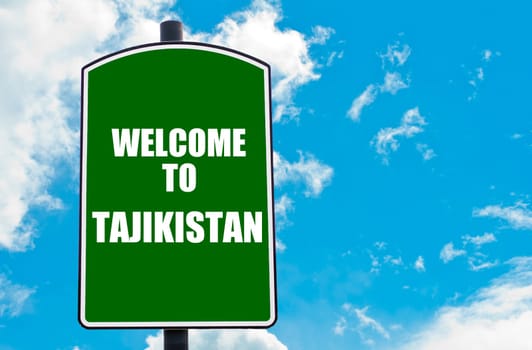 Green road sign with greeting message WELCOME TO TAJIKISTAN isolated over clear blue sky background with available copy space. Travel destination concept  image