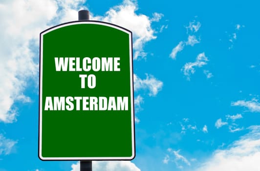 Green road sign with greeting message WELCOME TO AMSTERDAM, NETHERLANDS  isolated over clear blue sky background with available copy space. Travel destination concept  image