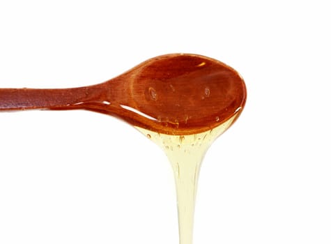 Wooden spoon with honey on white background photographed close up