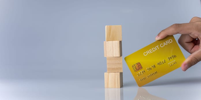 Hands holding credit cards and wooden cube blocks stacked on top of each other. Cashless spending concept.