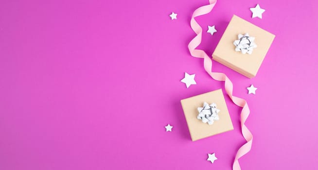 Christmas holiday background with little gift boxes, stars and fir branches, pink trendy background