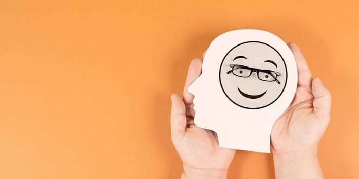 Holding a head with a happy smiling face, mental health concept, positive mindset, support and evaluation symbol