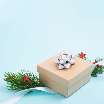Christmas holiday greeting card with little gift box, stars, ribbon and fir branches, blue background