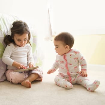 Caucasian girl children sitting on bedroom floor looking at book.